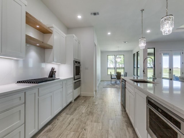 kitchen featuring visible vents, open shelves, a notable chandelier, a sink, and light countertops