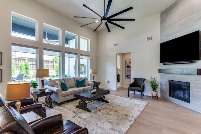 2313 Sandlin Dr, Fort Worth, TX 76008 - living area with light wood-style floors, a ceiling fan, visible vents, a high ceiling, and a tile fireplace
