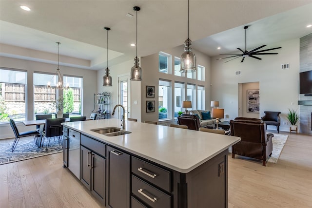 2313 Sandlin Dr, Fort Worth, TX 76008 - kitchen featuring ceiling fan with notable chandelier, light wood-type flooring, a kitchen island with sink, light countertops, and a sink