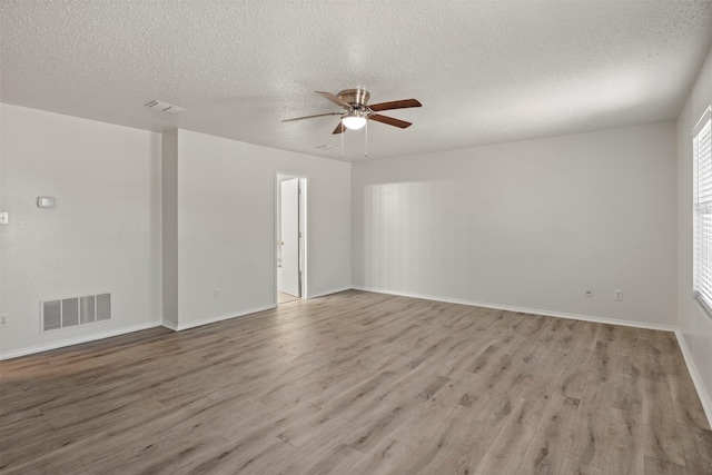 spare room featuring visible vents, a ceiling fan, light wood-style floors, and a textured ceiling