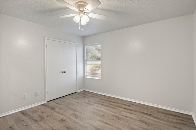 empty room with ceiling fan, baseboards, a textured ceiling, and wood finished floors
