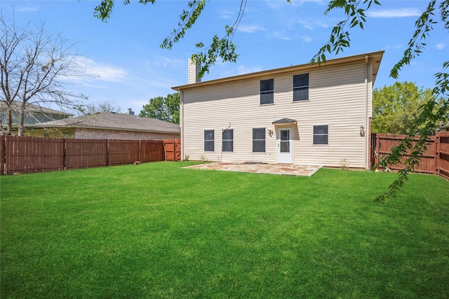 rear view of house featuring a yard, a patio, a fenced backyard, and a chimney