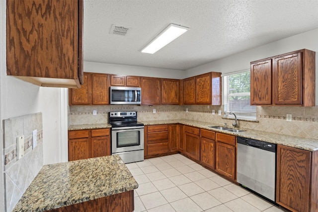 kitchen with a textured ceiling, a sink, visible vents, and stainless steel appliances