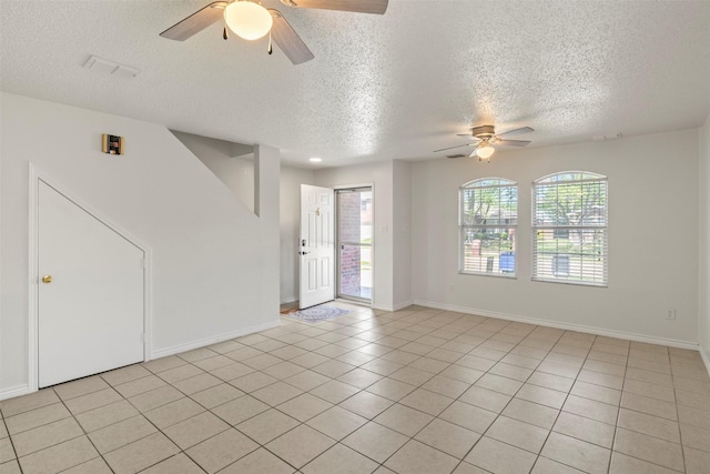unfurnished room with light tile patterned floors, a textured ceiling, a ceiling fan, and a healthy amount of sunlight