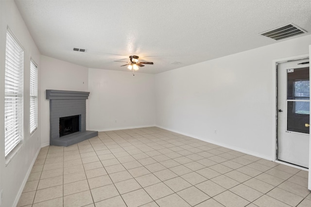 unfurnished living room featuring a fireplace, visible vents, a textured ceiling, and a ceiling fan