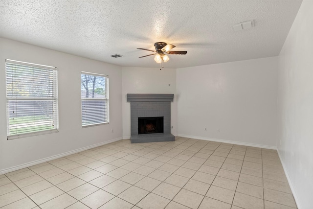 unfurnished living room with a textured ceiling, ceiling fan, a brick fireplace, and visible vents