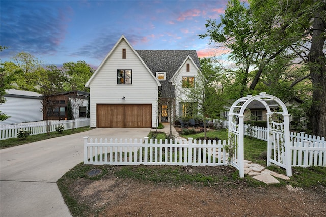 modern inspired farmhouse with a garage, driveway, and a fenced front yard