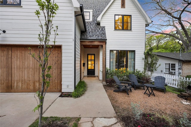 view of front of home with a patio area, fence, a garage, and roof with shingles