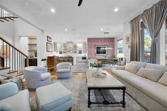 living area with recessed lighting, stairway, an inviting chandelier, and wood finished floors