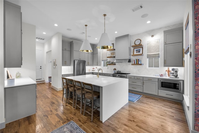 kitchen featuring visible vents, gray cabinets, stainless steel appliances, custom range hood, and decorative backsplash