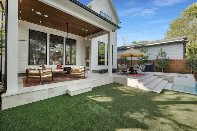 back of property with a patio, an outdoor hangout area, a jacuzzi, a yard, and fence