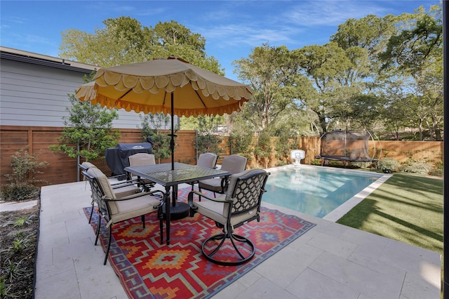 view of patio featuring a fenced backyard, a trampoline, and outdoor dining area