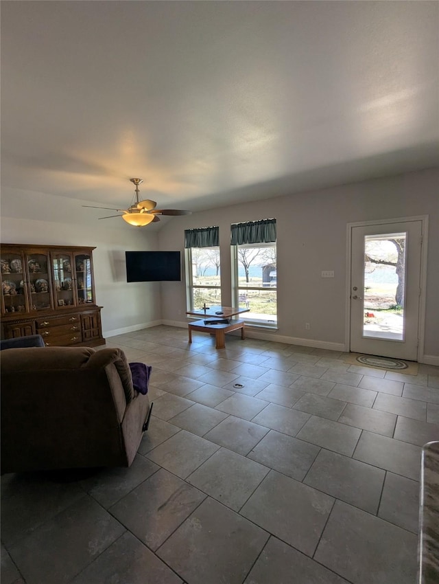 living room featuring a ceiling fan, baseboards, and tile patterned flooring