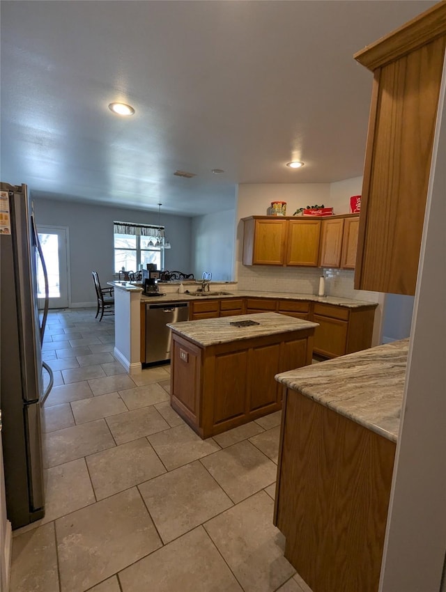 kitchen featuring brown cabinetry, a peninsula, recessed lighting, a sink, and stainless steel appliances