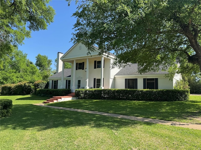 greek revival inspired property with a chimney and a front lawn