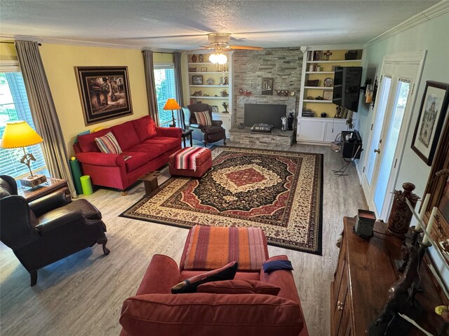 living area with built in shelves, ceiling fan, wood finished floors, and a fireplace
