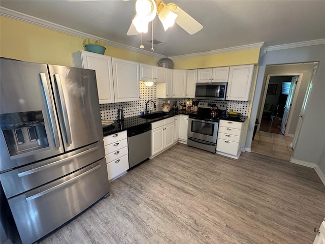 kitchen with dark countertops, white cabinets, appliances with stainless steel finishes, and light wood finished floors