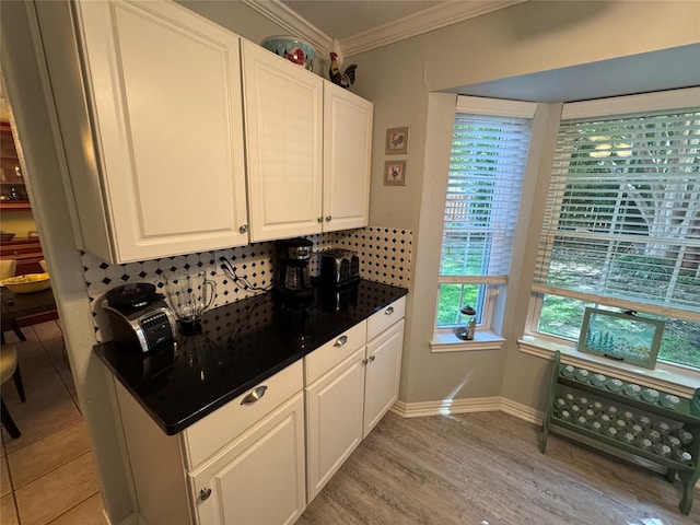 kitchen featuring white cabinets, crown molding, dark countertops, and plenty of natural light