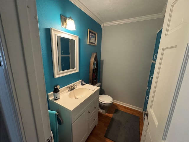 half bathroom featuring baseboards, toilet, crown molding, vanity, and wood finished floors