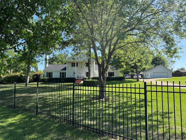 view of front facade featuring a garage, an outbuilding, a front lawn, and a fenced front yard