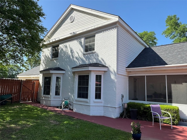 back of property featuring a sunroom, a yard, a patio area, fence, and brick siding