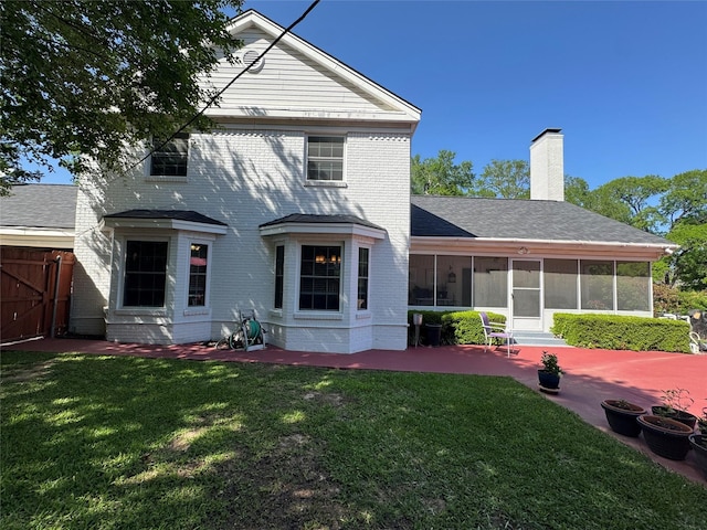 back of house with a chimney, a patio area, a sunroom, fence, and a lawn