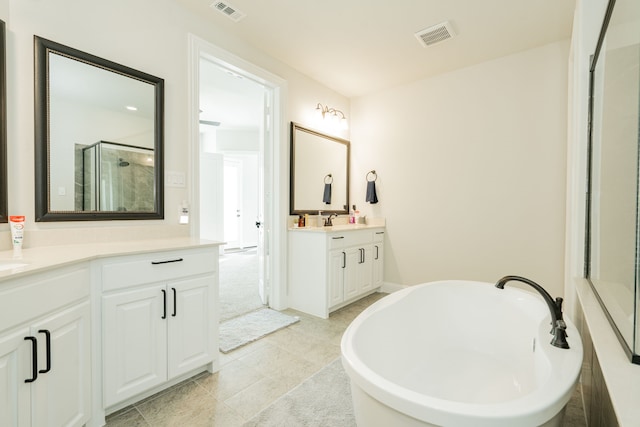full bathroom with two vanities, a shower stall, visible vents, a freestanding bath, and a sink