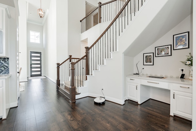 entryway featuring baseboards, a towering ceiling, and dark wood-style floors