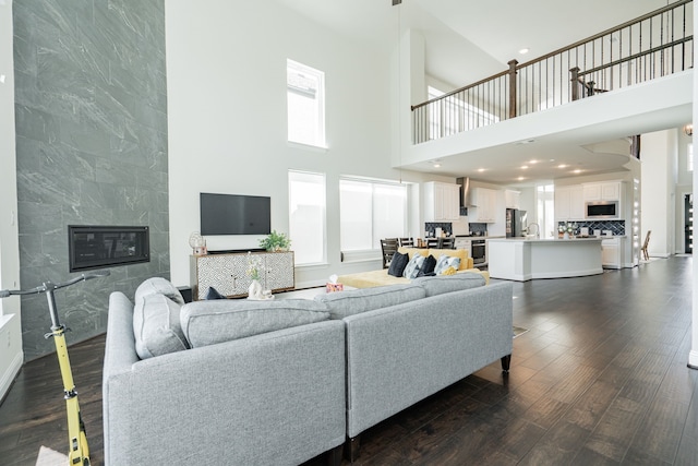 living area with a fireplace, dark wood-type flooring, and a high ceiling
