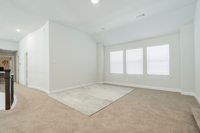 spare room featuring vaulted ceiling, visible vents, recessed lighting, light carpet, and baseboards