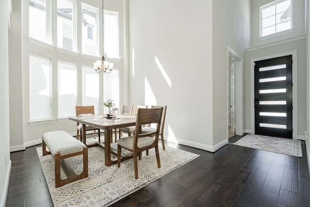 dining space featuring a chandelier, a high ceiling, baseboards, and dark wood-style floors