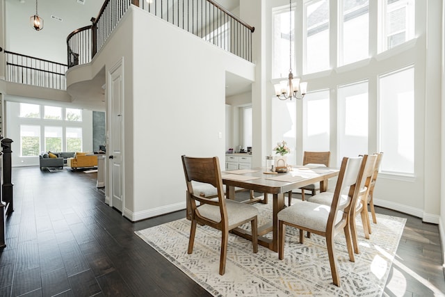dining space featuring baseboards, an inviting chandelier, a towering ceiling, and dark wood finished floors