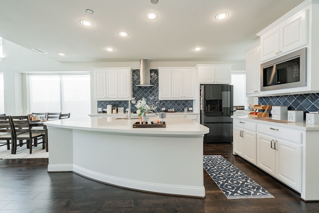 kitchen featuring tasteful backsplash, freestanding refrigerator, wall chimney exhaust hood, and built in microwave