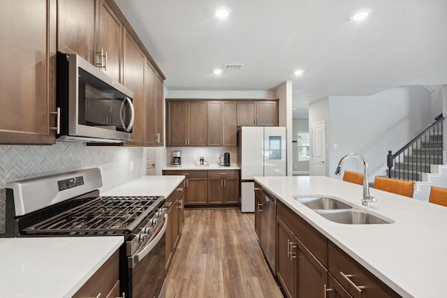 kitchen with stainless steel appliances, a sink, light wood-type flooring, visible vents, and light countertops