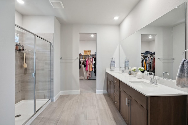 bathroom with a sink, a stall shower, double vanity, baseboards, and visible vents
