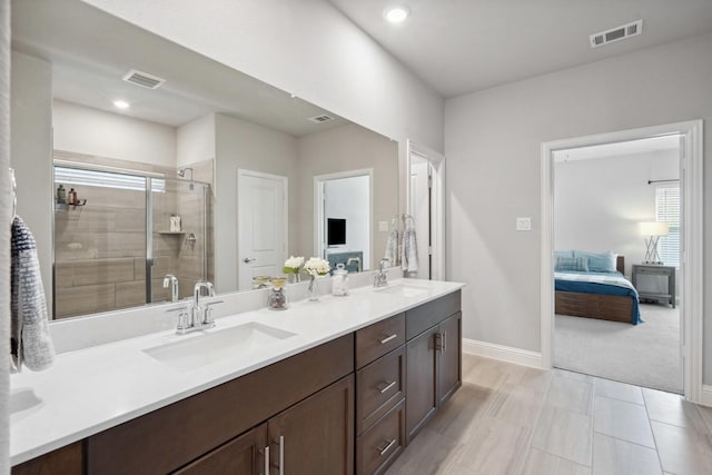 ensuite bathroom featuring a shower stall, a sink, and visible vents