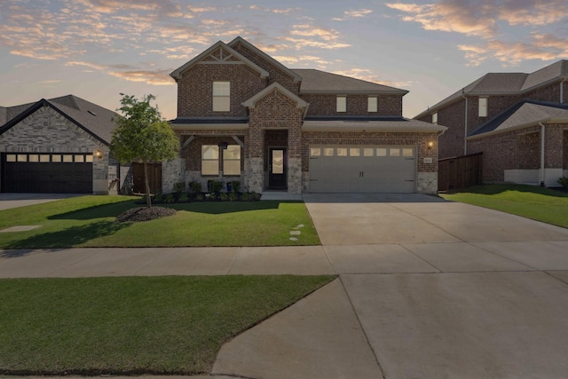 traditional-style house with a front lawn, driveway, stone siding, brick siding, and an attached garage