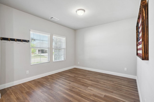 unfurnished room with dark wood finished floors, baseboards, and visible vents