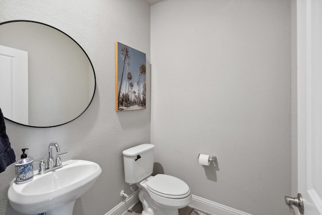 bathroom featuring baseboards, a sink, and toilet