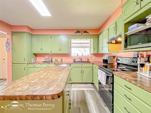 kitchen with a sink, light countertops, a center island, under cabinet range hood, and electric range