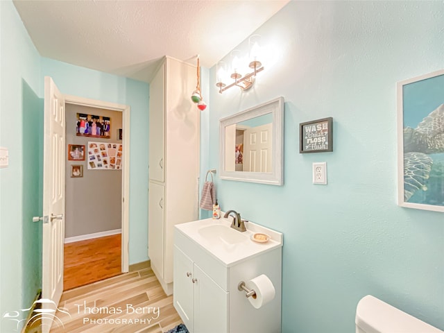 half bath featuring wood finished floors, toilet, and vanity
