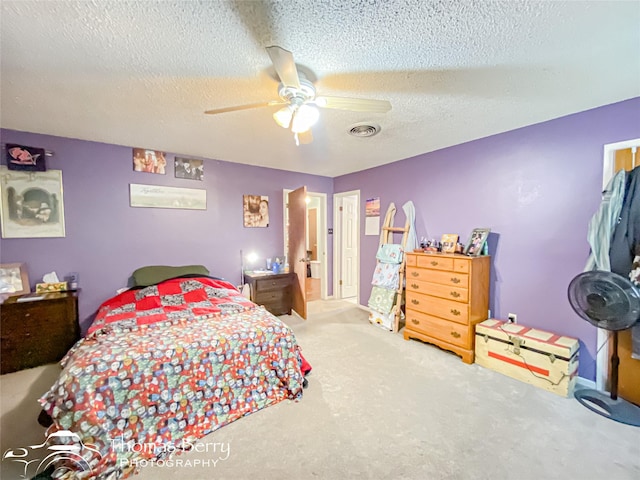 carpeted bedroom featuring visible vents, a ceiling fan, and a textured ceiling
