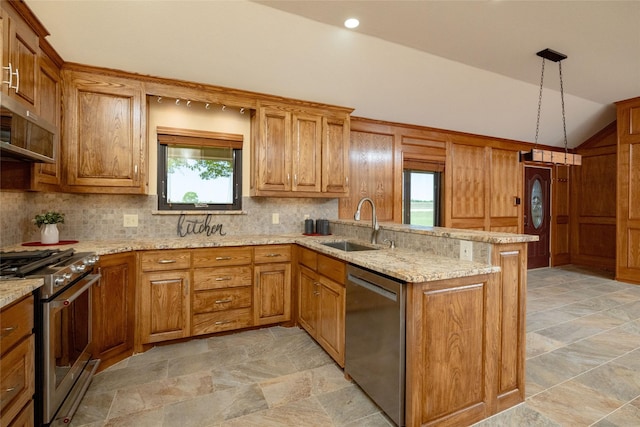 kitchen featuring brown cabinets, a sink, stainless steel appliances, vaulted ceiling, and a peninsula