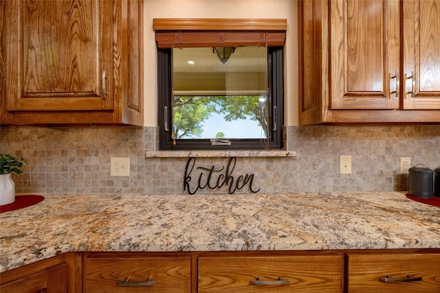 interior details featuring brown cabinetry, light stone counters, and decorative backsplash