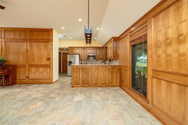 kitchen featuring brown cabinets, stainless steel appliances, stone finish flooring, a peninsula, and light countertops