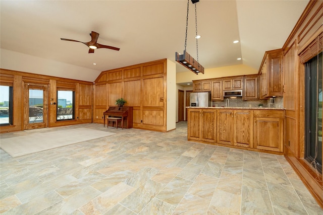 kitchen with lofted ceiling, brown cabinets, stone finish floor, and stainless steel appliances