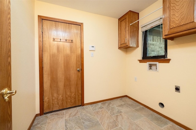 clothes washing area featuring hookup for an electric dryer, stone finish flooring, cabinet space, and baseboards