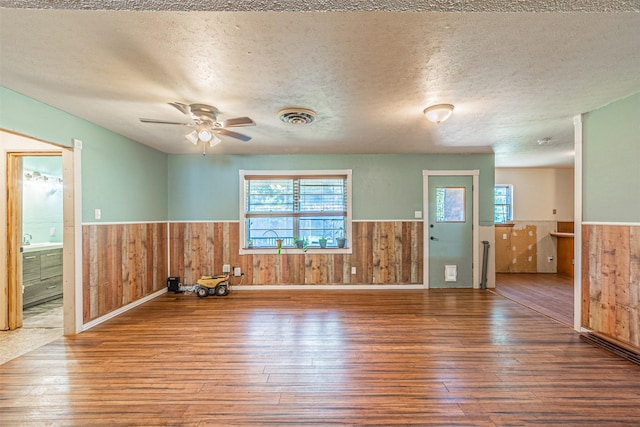 1206 John Reagan St, Benbrook, TX 76126 - empty room with wainscoting, wood-type flooring, wooden walls, healthy amount of natural light, and a ceiling fan