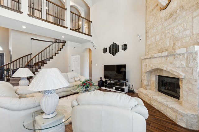 703 Sierra Ave, Mansfield, TX 76063 - living room featuring a towering ceiling, stairs, a stone fireplace, arched walkways, and wood finished floors