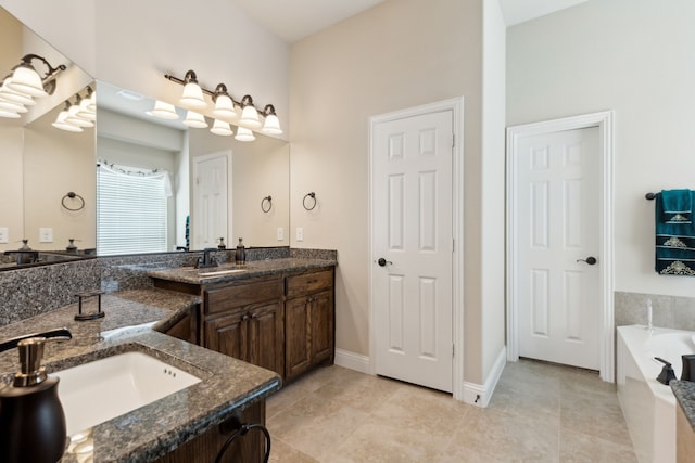 bathroom featuring tile patterned floors, vanity, baseboards, and a garden tub